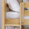 Close-up of natural wood bunk bed frame and ladder with white striped bedding and neutral decorative pillows