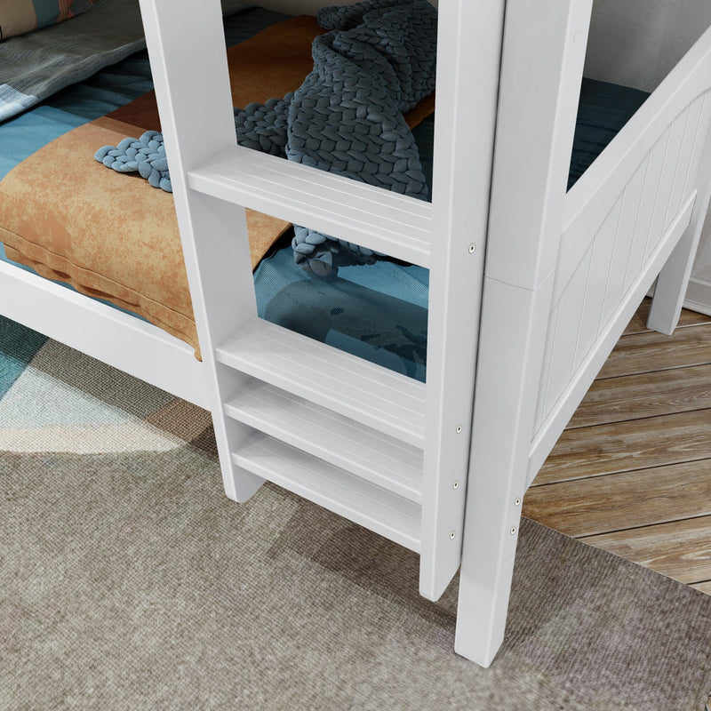 Close-up of a white wooden bunk bed ladder and slatted rail with a blue chunky knit blanket and tan bedding on the lower mattress, set on hardwood floor with a patterned area rug