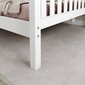 White bed frame on soft beige carpet in a cozy bedroom setting.
