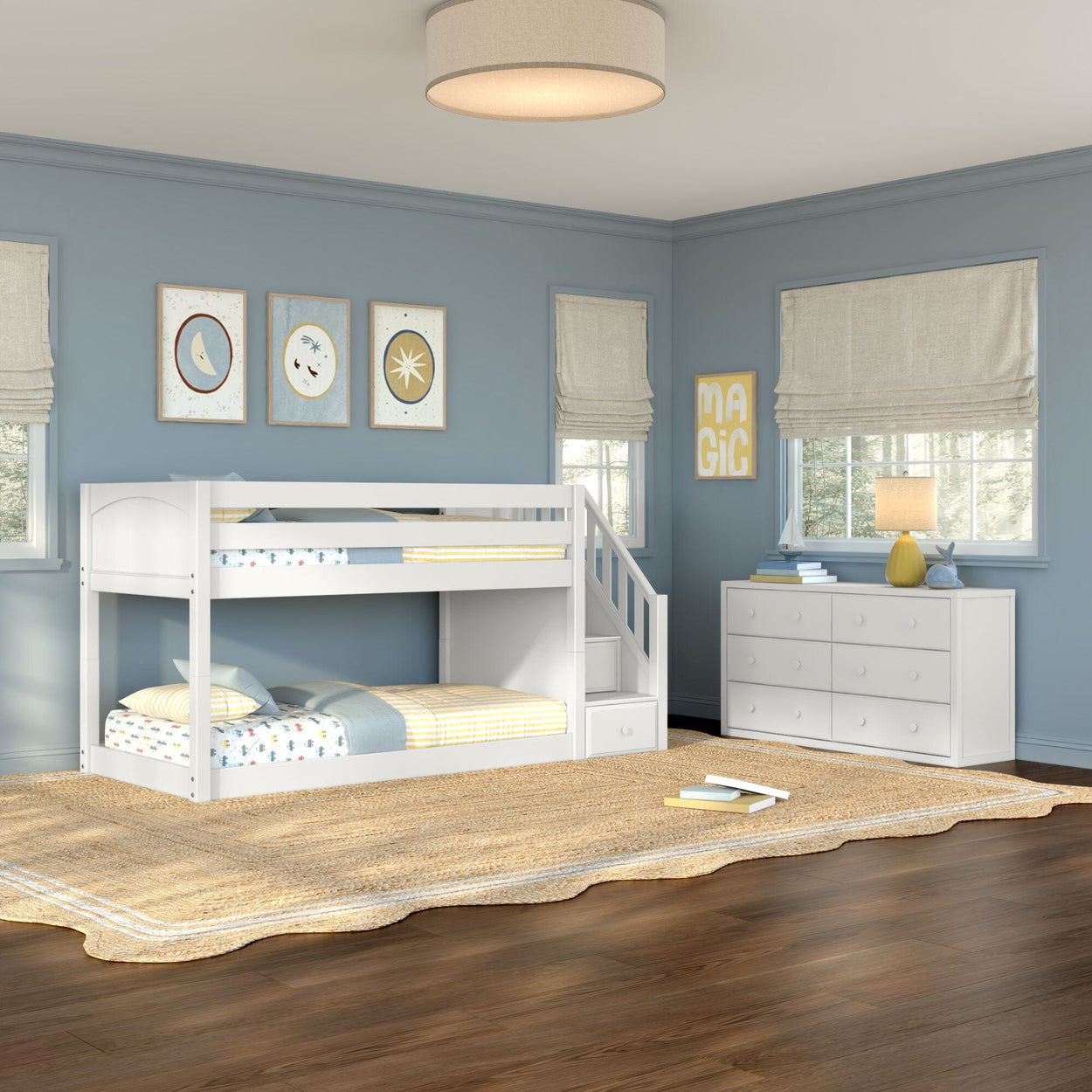 White wooden twin-over-twin bunk bed with staircase in a coastal-style kids' bedroom with blue walls, white dresser, woven jute rug and soft natural light.
