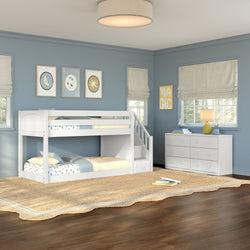 White wooden twin-over-twin bunk bed with staircase in a coastal-style kids' bedroom with blue walls, white dresser, woven jute rug and soft natural light.