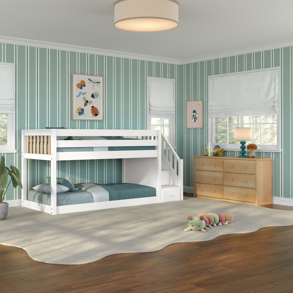Children's bedroom with white twin-over-twin bunk bed with stairs and storage, teal vertical striped wallpaper, light wood dresser, cream area rug and plush caterpillar toy