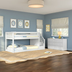Kids room with white twin-over-twin bunk bed with stairs, blue painted walls, woven jute rug, white dresser, lamp and wall art
