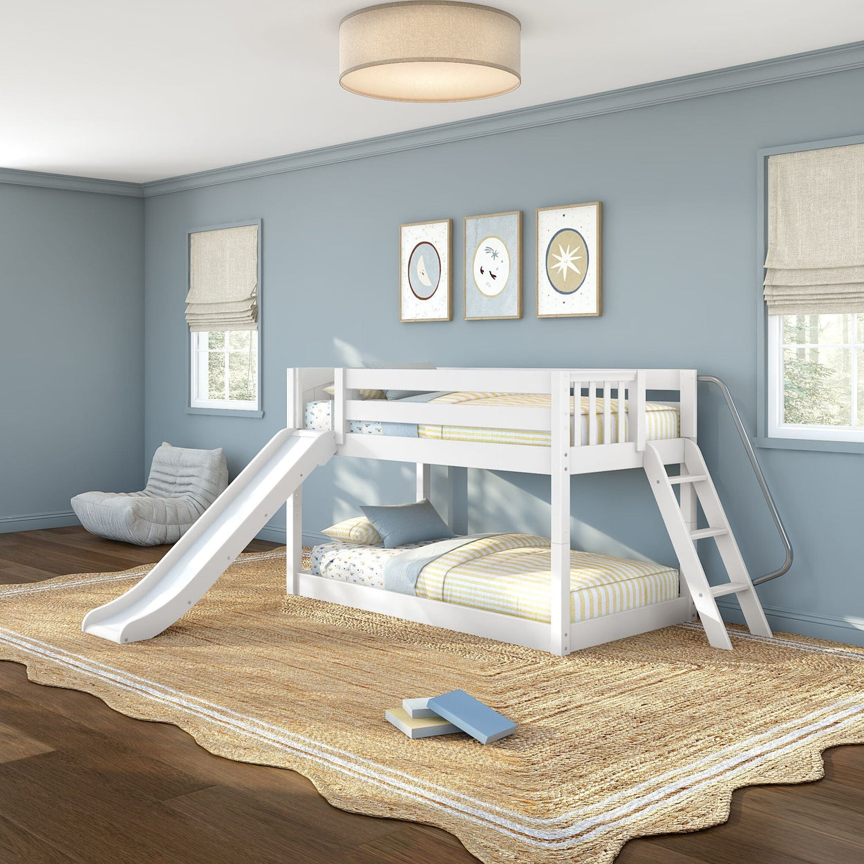 White twin-over-twin bunk bed with slide and ladder in a modern blue kids bedroom with striped bedding, natural jute rug, framed wall art, and large windows