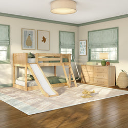 Children's room with natural wood twin-over-twin bunk bed with slide, green-striped Roman shades, wooden dresser and play rug on hardwood floor
