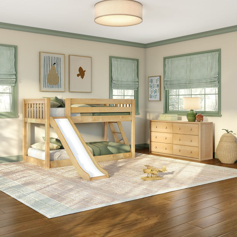 Natural wood kids bunk bed with slide in bright children's bedroom featuring green-trimmed windows, striped Roman shades, wooden dresser, toy airplane, neutral area rug and hardwood floors