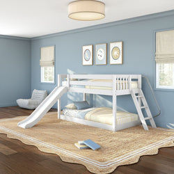 White wooden bunk bed with slide and ladder in a modern blue children's bedroom with striped bedding, natural jute rug, hardwood floors, wall art and Roman shades