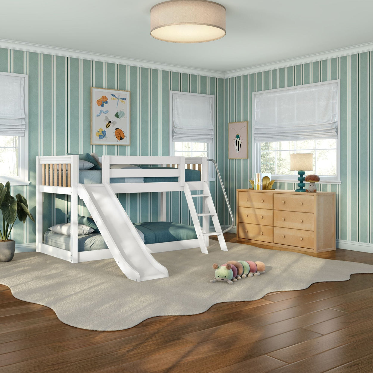 White wooden kids bunk bed with slide in a bright teal-striped bedroom with hardwood floors, plush rug, wooden dresser and playful wall art