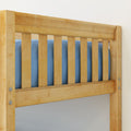 Light wood slatted bed headboard with vertical slats, blue bedding visible and metal bolt hardware on frame
