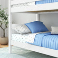 White wooden bunk bed with blue quilted bedding and star-print sheets in modern kids' bedroom with potted plant