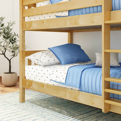 Wooden bunk bed with blue bedding and decorative pillows in cozy bedroom.