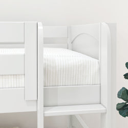 White wooden loft bed with striped bedding and ladder, next to a green plant in a light-filled room.