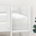 Close-up of a white wooden bunk bed showing ladder, guardrail, and white quilted bedding in a modern kids' bedroom