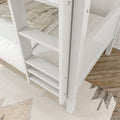 Close-up of white wooden bunk bed ladder with slatted steps, beige plaid bedding and hardwood bedroom floor