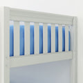 White wooden baby crib close-up showing vertical slats and blue mattress bedding in a modern nursery, highlighting crib rail safety detail