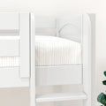 Close-up of a white wooden twin-over-twin bunk bed with protective guardrail and neutral plaid bedding in a modern kids' bedroom.