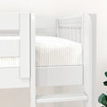 Close-up of white wooden bunk bed with vertical slats, ladder and striped white bedding in a modern kids' bedroom