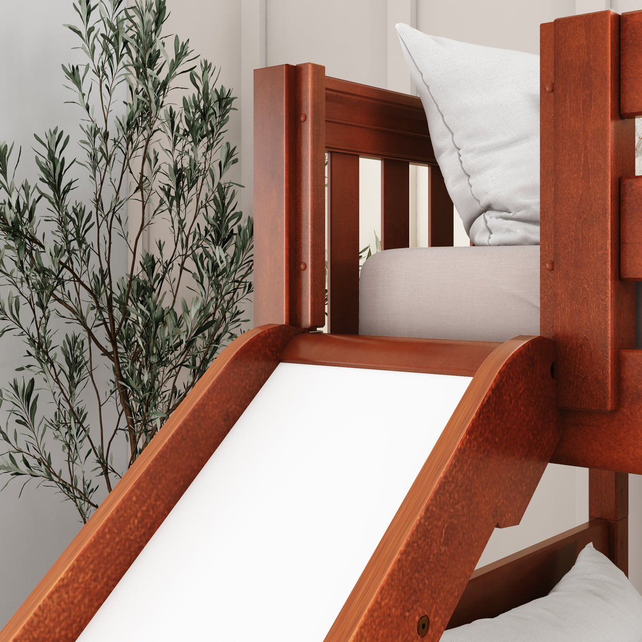 Kids' wooden loft bed with slide and white pillow, indoor plant decor.