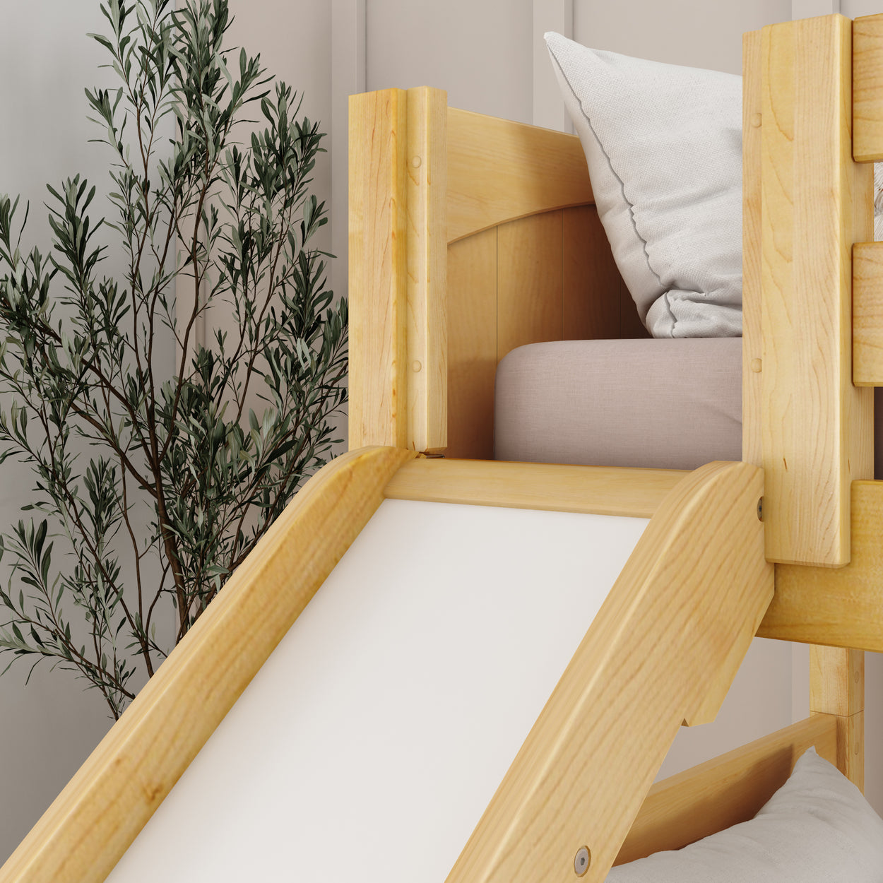 Wooden children's bed with slide and comfortable pillows in a cozy interior setting.