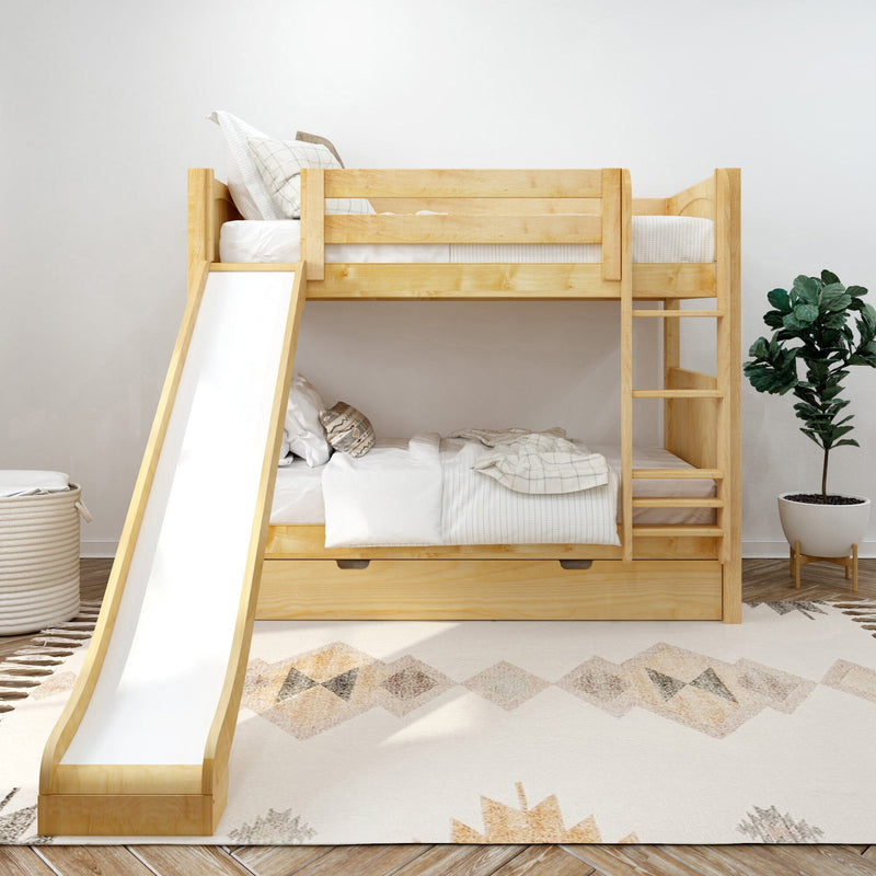 Natural wood twin-over-twin bunk bed with slide and under-bed storage in a bright kids' bedroom with white bedding, geometric rug and potted plant