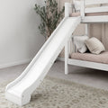 White wooden kids bunk bed with slide, blush mattress and neutral pillows in a modern nursery bedroom with potted plant and patterned rug