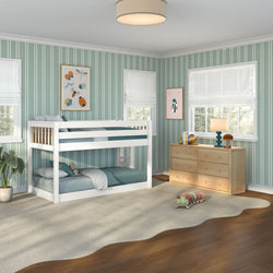 Kids bedroom with white twin-over-twin bunk bed, teal striped wallpaper, light wood dresser, plush caterpillar toy, soft beige area rug and sunlit windows