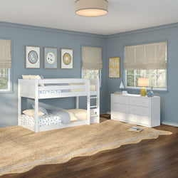 White twin-over-twin bunk bed in blue children's bedroom with white dresser, jute rug, hardwood floors, roman shades and wall art
