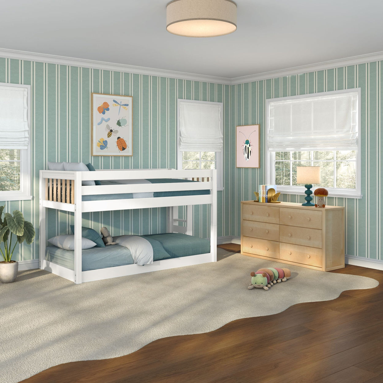 Children's bedroom with white twin-over-twin bunk bed, teal vertical striped walls, light wood dresser, white Roman shades, hardwood floor and plush caterpillar toy
