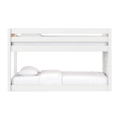 Modern white painted-wood bunk bed with upper safety guardrail and white bedding, minimalist children's bedroom furniture