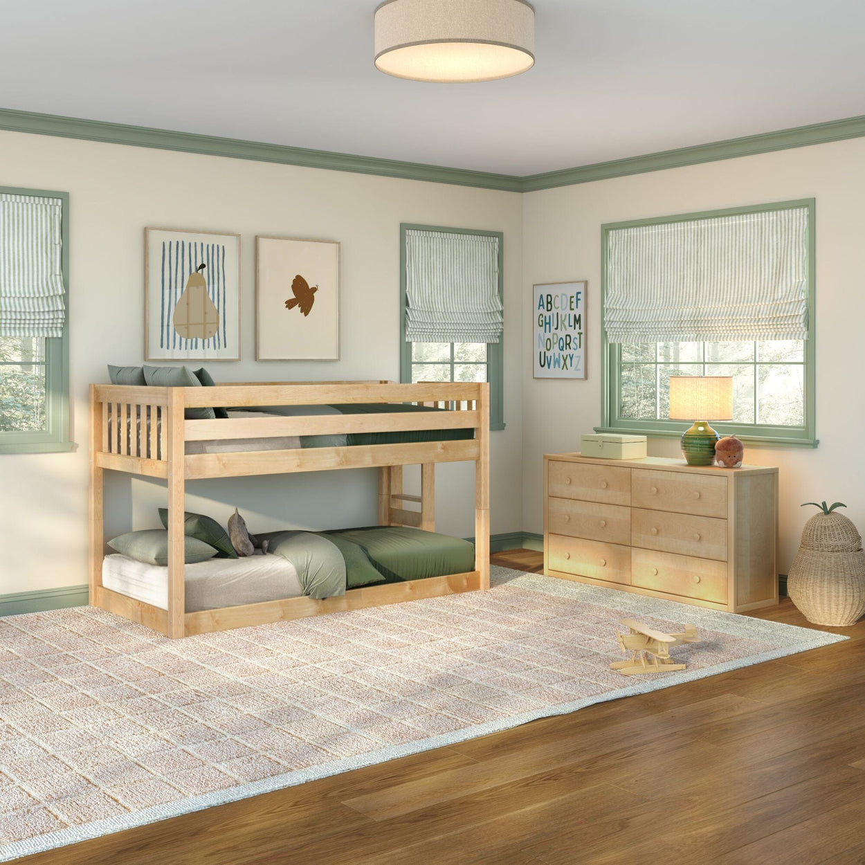 Kids bedroom with natural wood bunk bed, green bedding, wooden dresser, alphabet wall art, roman shades and area rug on hardwood floor