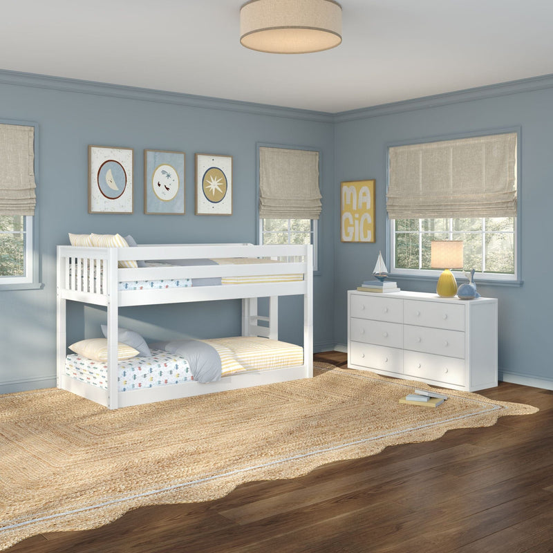 Children's bedroom with white bunk bed, blue walls, framed moon and star artwork, beige roman shades, white dresser and woven rug