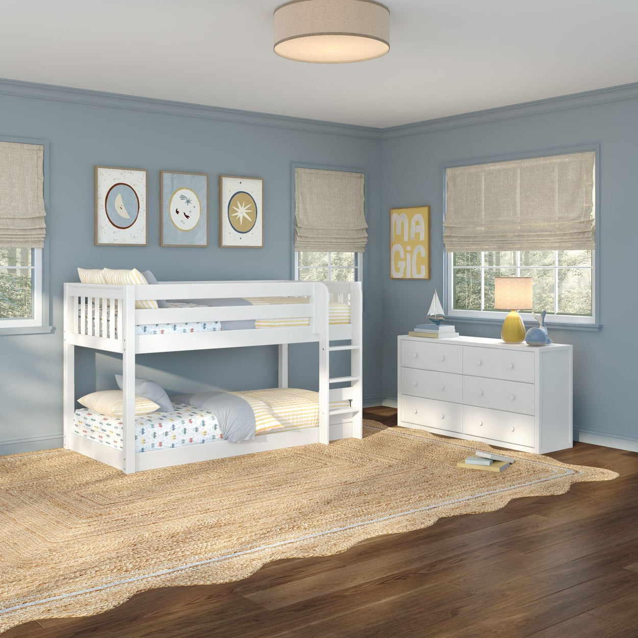 Kids bedroom with white wooden bunk bed, blue painted walls, white six-drawer dresser, natural woven jute rug, Roman shades and nautical wall art