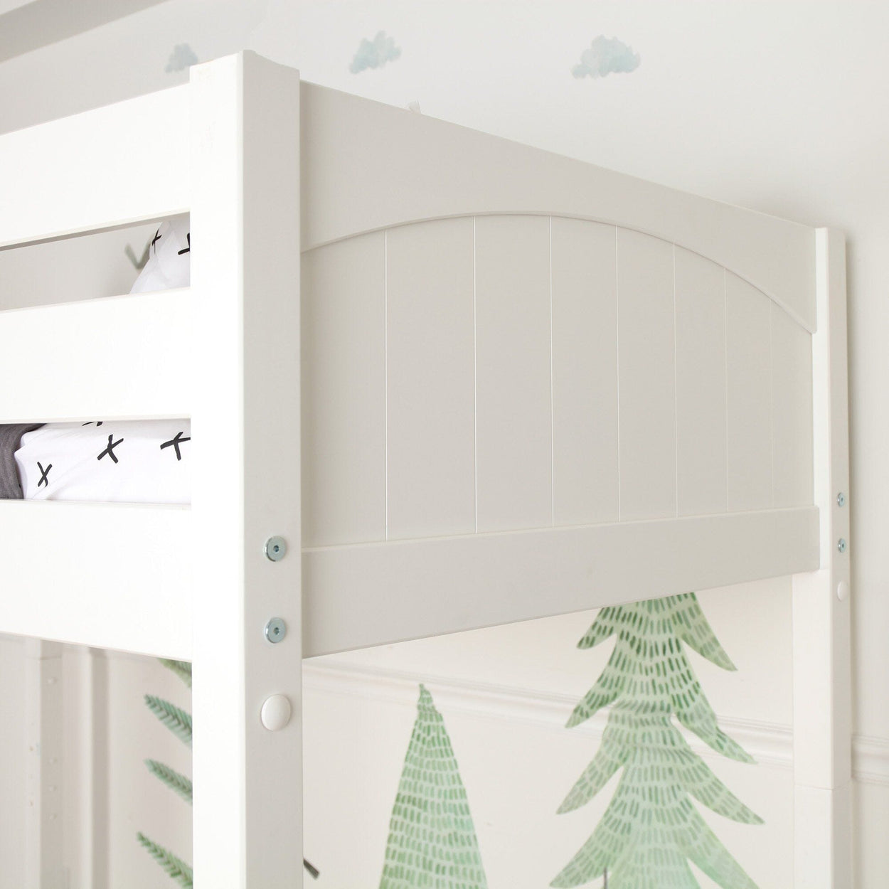 White wooden loft bunk bed with arched plank headboard and safety rail in a modern kids' bedroom featuring green pine tree wall decals and cloud stickers