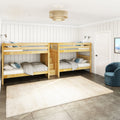 Natural wood bunk beds in bright modern farmhouse kids' bedroom with white shiplap walls, layered bedding and woven ceiling light