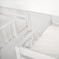 Close-up of white painted wooden bunk bed guardrail and mattress on a minimalist twin bed frame in a child's bedroom