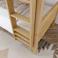 Close-up of a solid natural wood bunk bed ladder and slats with white plaid bedding, light hardwood floor and patterned rug