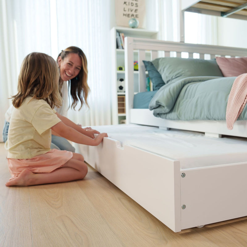 Kids bedroom with white bunk bed and pull-out trundle bed, smiling mother helping daughter make bed