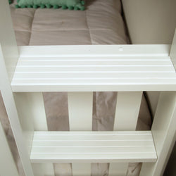 White wooden ladder steps for bunk bed with cozy bedding in background.