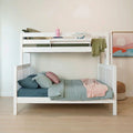 White wooden bunk bed with sage green bedding, pink throw and pillows, plush dinosaur toy and pastel wall art in modern kids' bedroom