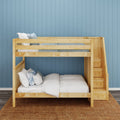Natural wood bunk bed with built-in storage stairs against blue paneled wall, white bedding and blue accent pillows in kids' bedroom