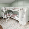 White triple bunk bed with ladder and built-in storage stairs in pastel green paneled kids' bedroom with cozy bedding and decorative pillows