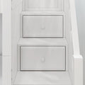 Close-up of white custom built-in under-stair storage drawers with shaker-style panel fronts and round knobs