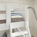 White wooden bunk bed with ladder, blue-striped quilt and tassel throw in a cozy farmhouse-style kids' bedroom with paneled beige wall