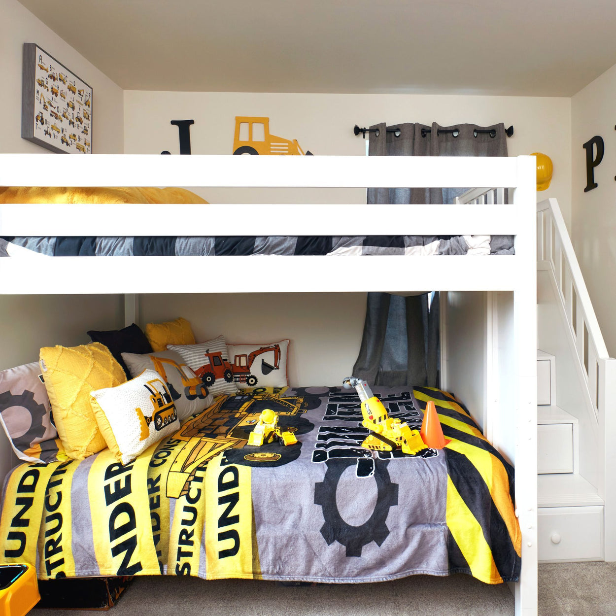 Kids' construction-themed bunk bed with yellow and black bedding, toy trucks, and playful decor.