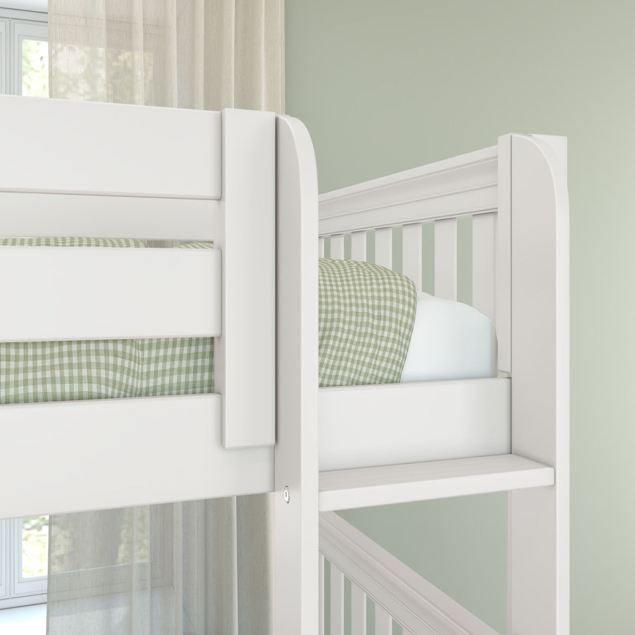Close-up of a white wooden bunk bed with green gingham bedding, safety rails and ladder in a soft-green modern nursery with sheer curtains