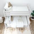 Top-down view of a white wooden bunk bed with crisp white linens, neutral throw pillows, checkered blanket and potted plant in a modern kids' bedroom