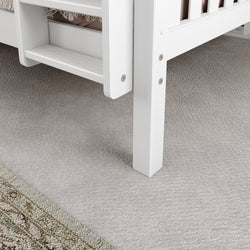 White wooden bunk bed with ladder on soft beige carpet flooring.