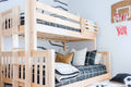 Light wood twin-over-twin bunk bed in kids bedroom with plaid bedding, ladder, built-in book shelf and indoor basketball hoop