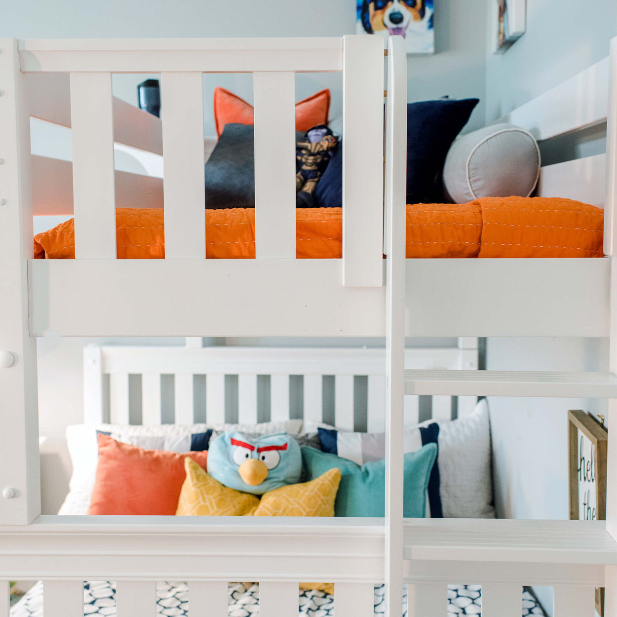 White bunk bed with colorful pillows and orange bedding in a child's cozy bedroom.