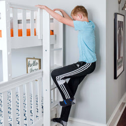 Boy climbing a white bunk bed ladder in a modern bedroom.
